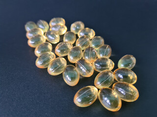 Omega 3 capsules of vitamin D and E on black background