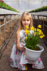 Young girl in flower greenhouse. Outdoors spring kid portrait