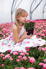 Young girl in flower greenhouse. Outdoors spring kid portrait