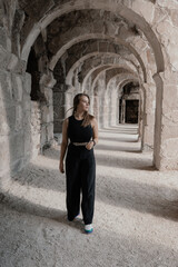 Fototapeta na wymiar a girl in black clothes walks through antique arches