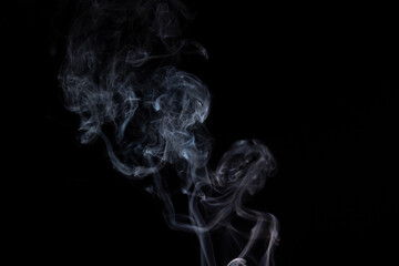 incense stick with white smoke against black background