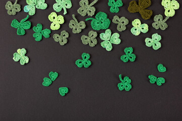 St Patrick's Day concept. Composition made of knitted green shamrocks on a black background....
