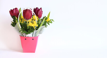 Bouquet of spring flowers with tulips in a pink cardboard basket. Spring flowers on a white background. Flowers with empty space nearby. Photo to create postcards