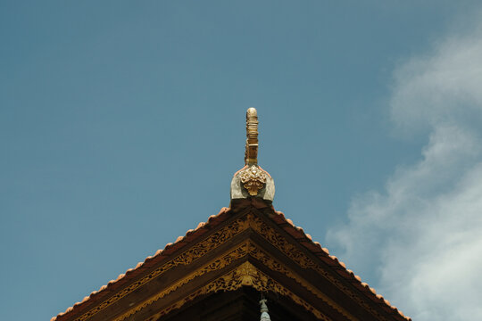 The intricate roof design of a temple set against a clear blue sky creates a picturesque and serene image