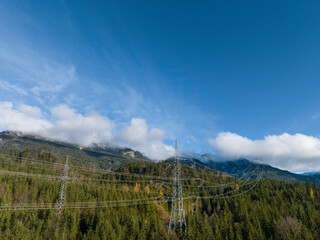 view of 110kV power high-voltage line in the middle of the forest on large metal pylons for long-distance energy transport