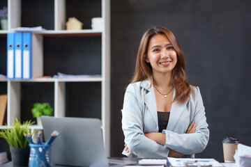 Beautiful asian businesswoman sitting crossed arms smiling looking at camera in office.