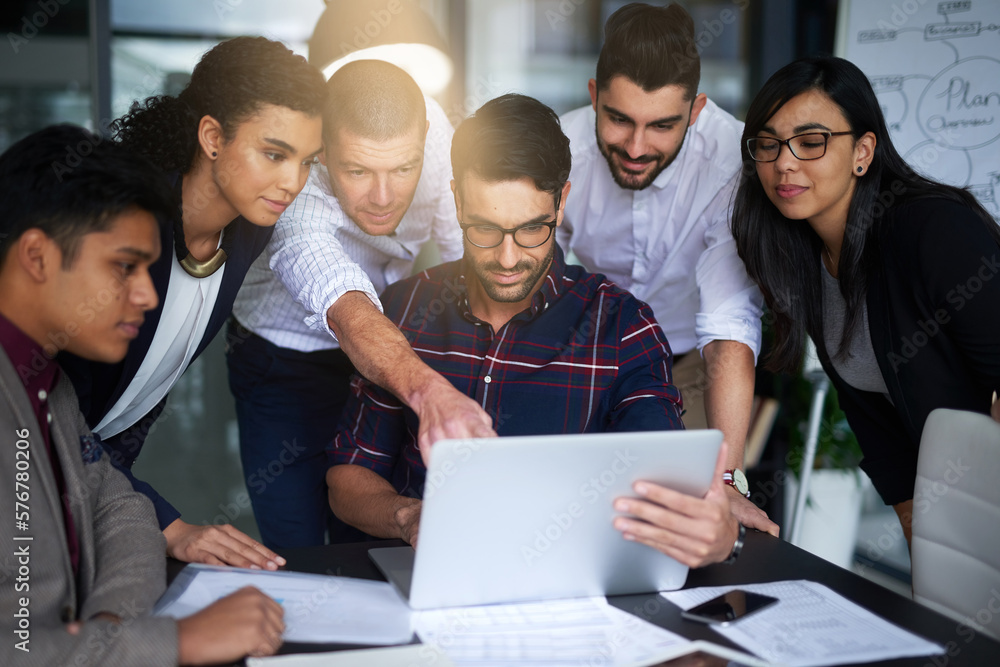 Poster they work seamlessly together. shot of a group of colleagues working together around a laptop in an 