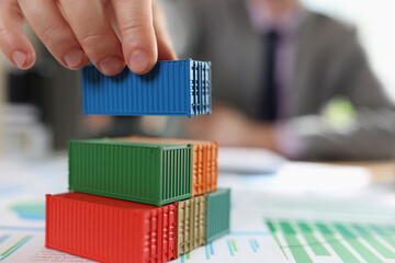 Man putting cargo containers on stack on financial report papers