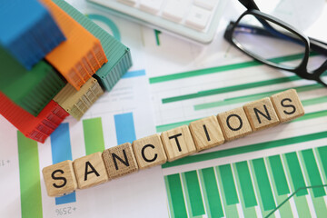 Sanctions word collected with wooden cubes in row on financial documents