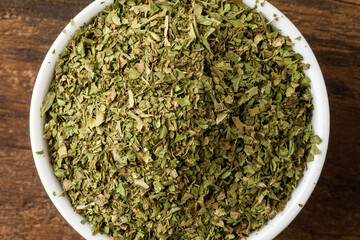 Lovage leaves in bowl on rustic wooden table. Top view