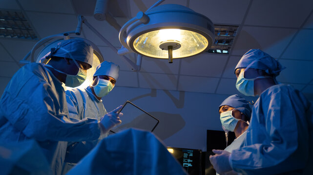 The medical team discussed the surgical options with the patient before proceeding with the operation. Surgeons team operating a patient in the operating room at the hospital