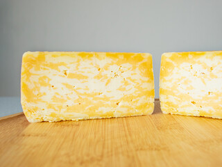 cut marble cheese head on a wooden cutting board, close up, hard cheese