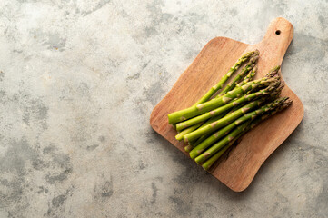 Fresh asparagus on wooden chopping board, top view. Copy space.