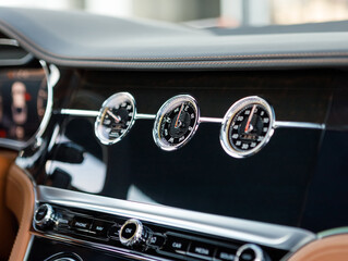 mechanical clock and other gauges on luxury car dashboard
