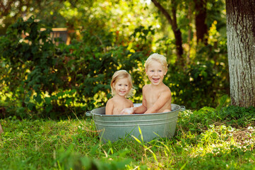 Little baby's bathes in a basin, laughs and splashing his hands in water and making splashes. Summer days concept, holidays, rest