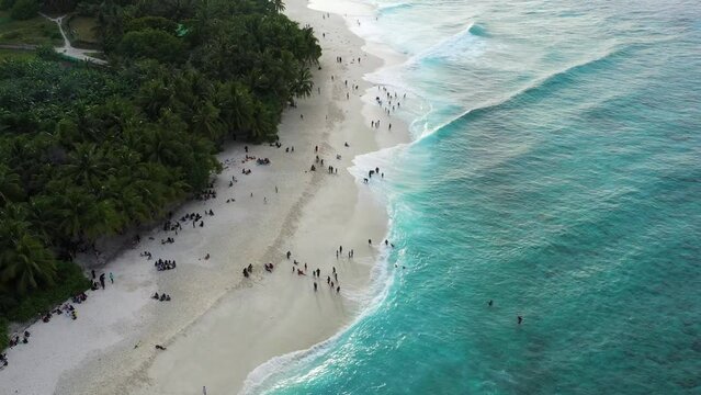 Aerial view of people on the beach along the shoreline on Maldives Islands.