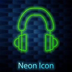 Glowing neon line Headphones icon isolated on brick wall background. Earphones. Concept for listening to music, service, communication and operator. Vector