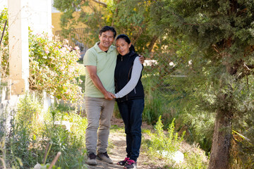 Portrait of Hispanic couple outside their house in the neighborhood - Latin couple taking a walk in nature - Retired adults walking in the park