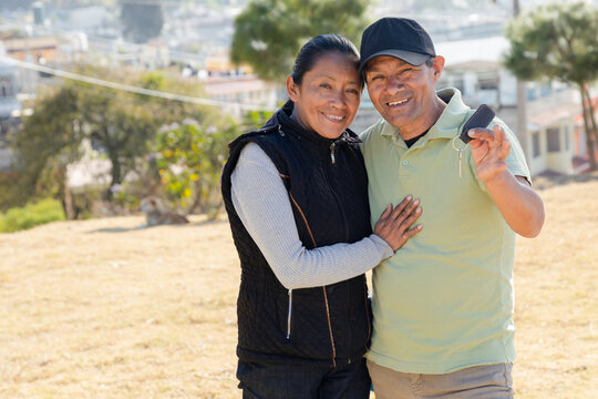 Latin couple with a key in hand - happy homeowners - Hispanic buying a house - Mortgage concept