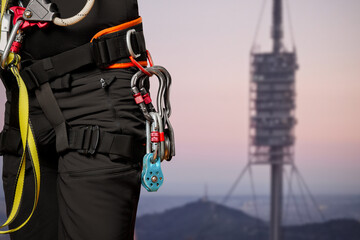 High-altitude equipment, carabiners, block rollers, on a man's belt. Telecommunications, work at height, industrial mountaineering, height, insurance. Close-up. Cell tower.