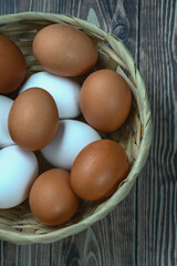 several fresh chicken eggs in a straw basket on a wooden background. Healthy eating concept