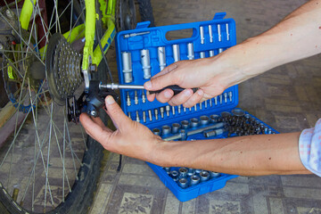 male hands repairing a bicycle,rear derailleur adjustment on a bicycle, bicycle repair shop - obrazy, fototapety, plakaty