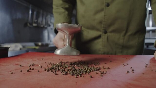 Close-up of black pepper, which the chef smashes with an iron hammer. Put hot peppers on a cutting board. High quality 4k footage