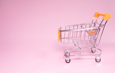 Close-up of shopping trolley on pink background with some copy space. Shopping concept.