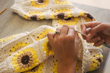 woman knitting at home cardigan with squares of sunflowers crochet grannys