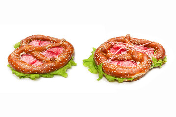 Pretzel with salami and lettuce isolated on a white background.