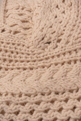 A fragment of beige knitted fabric, knitted from white sheep wool.
