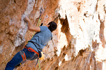 Young man is climbing on the rocks in the mountains.