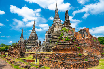 Fototapeta premium Ruins of ancient city and temples Ayutthaya, Thailand. Old kingdom of Siam. Summer day with blue sky. Famous tourist destination, spiritual place near Bangkok.