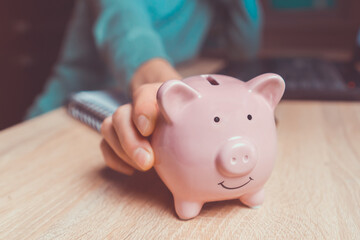 The girl puts her savings in a piggy bank.