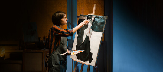 A girl is working on oil painting artwork in her workshop.
