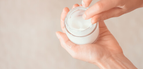 Female hands hold a jar of moisturizing cream.