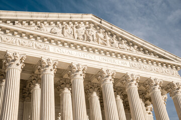 Imposing facade of the United States Suprement Court in Washington, DC with blue sky.