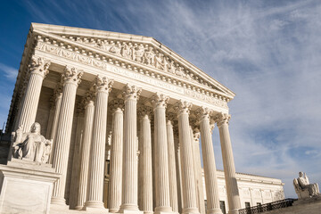 Imposing facade of the United States Suprement Court in Washington, DC with blue sky.