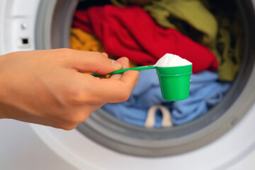 Female hand holds a cap with washing powder.
