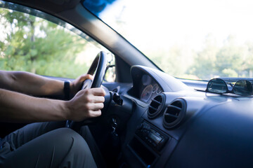 Naklejka premium A man is driving a car, hands on the steering wheel closeup.