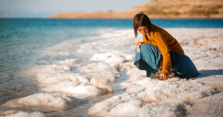 Girl is travelling, sitting on the shore og the Dead Sea.