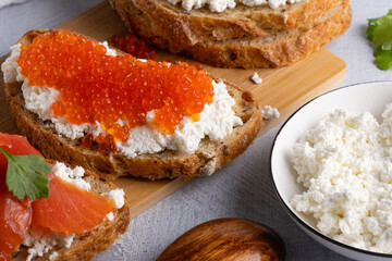 Sandwiches with red caviar, cottage cheese and salted salmon. Wooden cutting Board. Close up