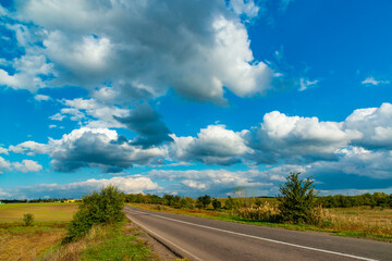 Fototapeta premium White cumulus thunderclouds in the sky over a highway, Ukraine