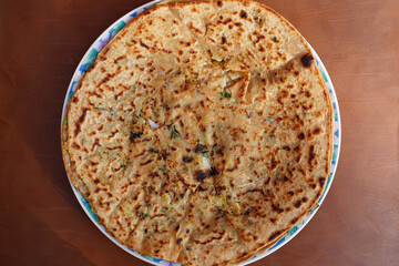 Potato stuffed paratha, aloo vali roti, torn in the middle for the filling visibility, top view.  A round oriental flatbread stuffed with potato, onion, herbs, spices, popular in the Punjab. Close-up.