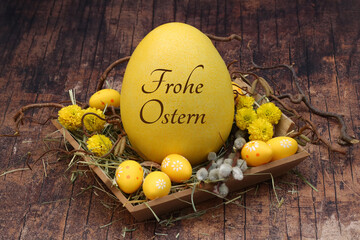 Grußkarte Frohe Ostern: Osternest mit gelben Ostereiern und einem beschrifteten Osterei. - obrazy, fototapety, plakaty