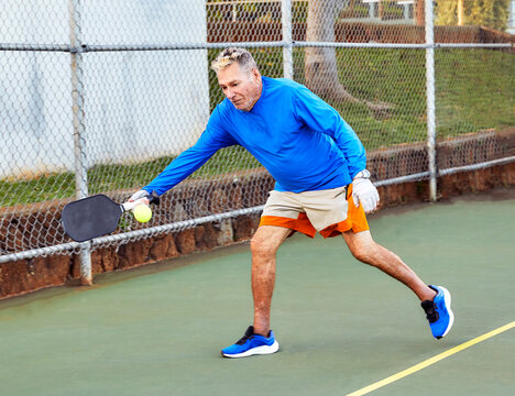 Active Senior Man playing Pickle Ball outdoors