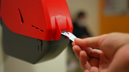 Closeup of Waiting Number Machine. Customer hand pulls a numbered ticket in dispenser machine. wait...