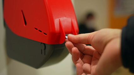 Closeup of Waiting Number Machine. Customer hand pulls a numbered ticket in dispenser machine. wait...