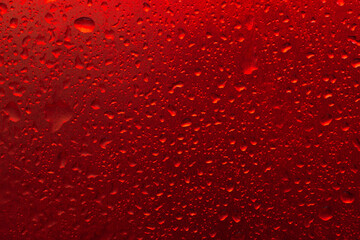 The texture of a water drop on a red background close-up