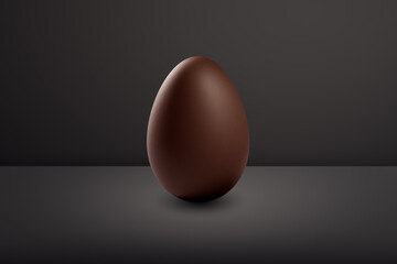 milk chocolate Easter egg in front of a black wall and on a black floor